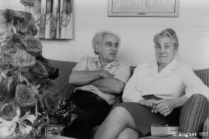Julius Sumner Miller and his wife Alice sitting together on a sofa, roses in the foreground, photographed in Sydney in August 1977