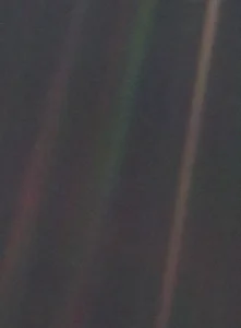 The Pale Blue Dot image, showing Earth as a point of light within a band of scattered sunlight against black space