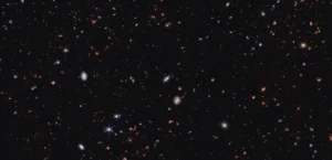 A vast black field of space scattered with hundreds of tiny red and orange dots.